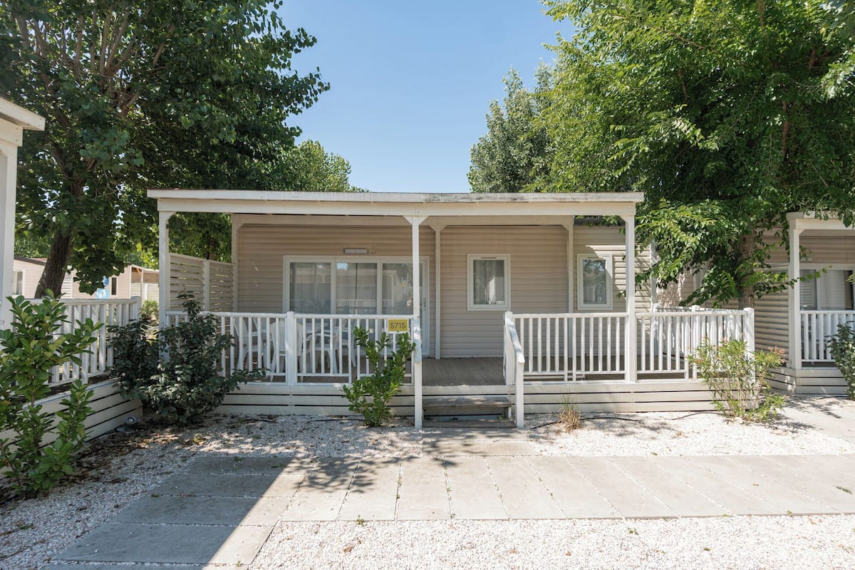 A single-story mobile home with a porch, a door, and a window.