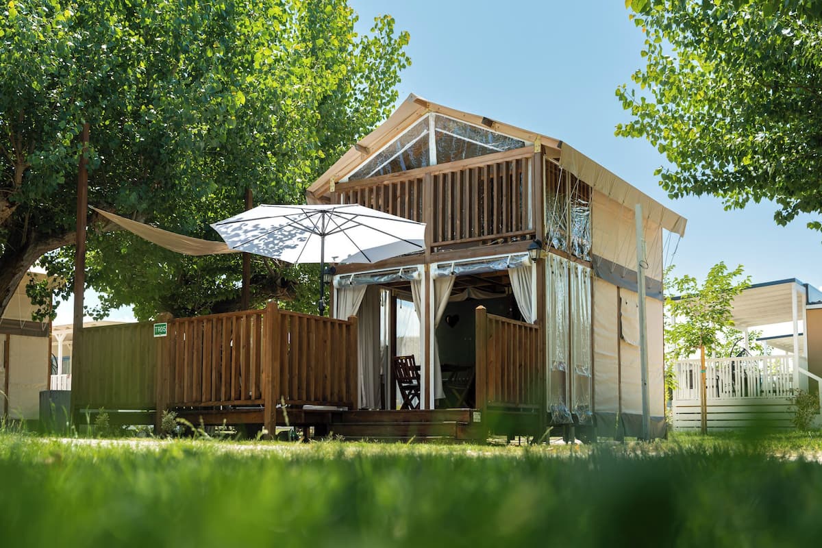 A wooden house with a covered porch, a table, and an umbrella.