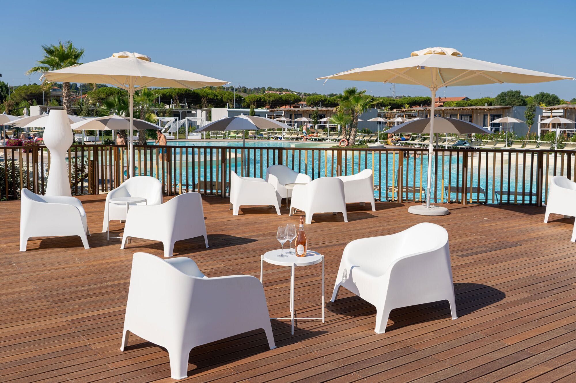 Una terrazza con sedie e ombrelloni bianchi, con vista su una piscina.