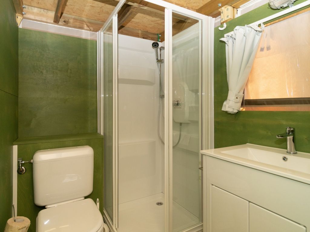 Een badkamer met douche, toilet en wastafel.