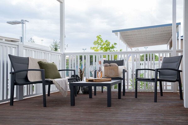 A covered outdoor seating area with two chairs, a table, and a bottle of wine. - Club del Sole Romagna Family Village Riccione. (Riccione)
