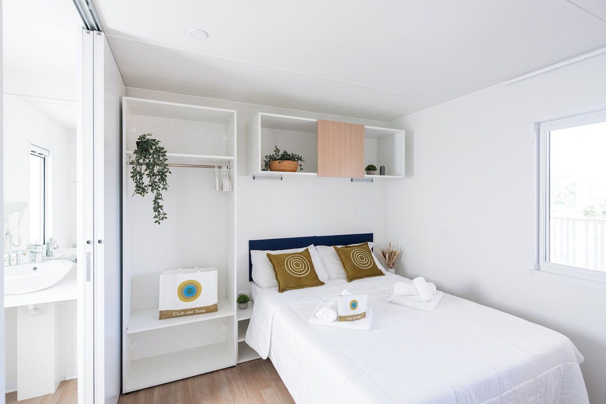 A hotel room with a bed, a white wardrobe, a bathroom, and a window.
