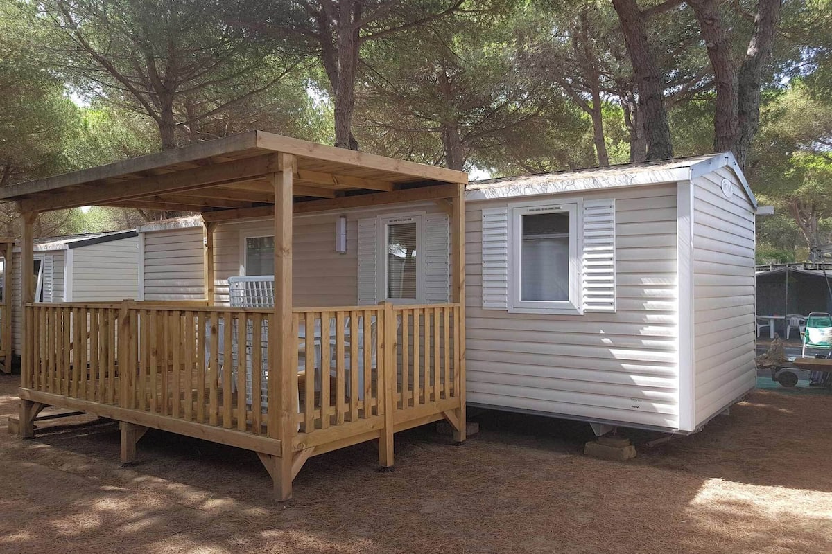 Une terrasse en bois attenante à une maison mobile, avec un porche couvert.