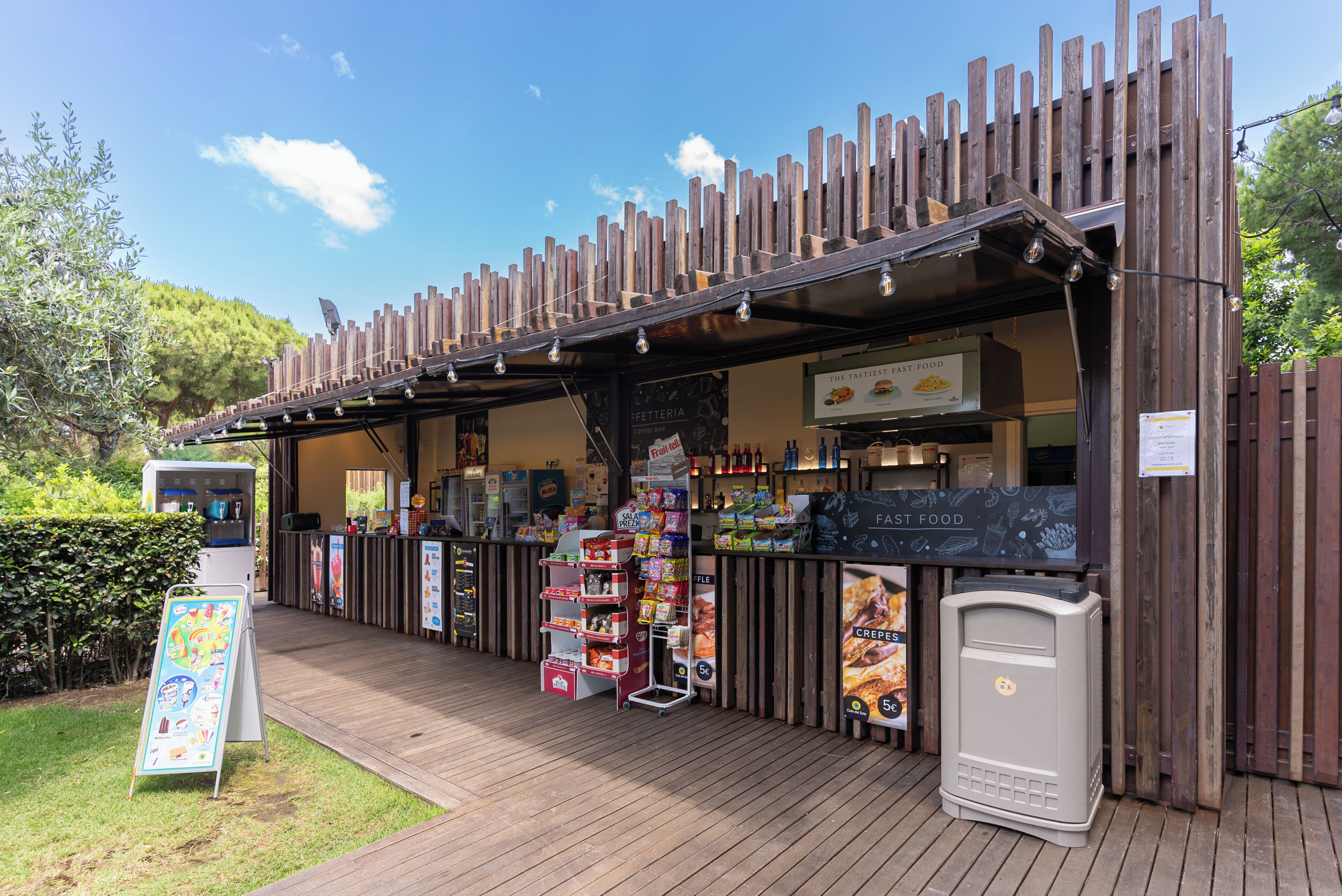 A food kiosk with a wooden exterior, a signboard, and a vending machine.