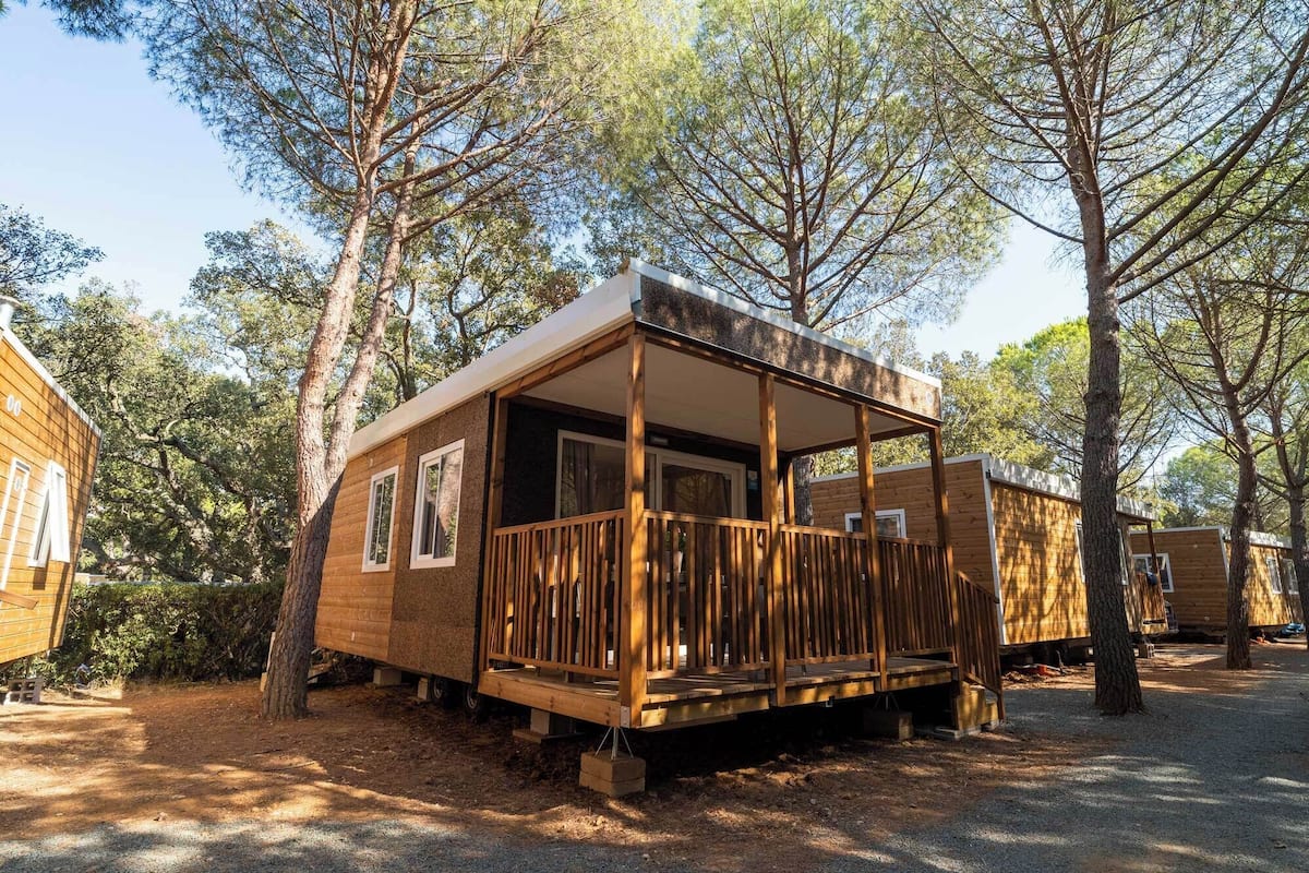 A wooden cabin with a porch, surrounded by trees.