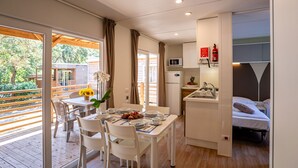 A compact hotel room with a balcony, a kitchenette, and a bed.