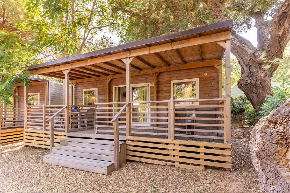 A wooden cabin with a porch, multiple windows, and a number '550' sign.