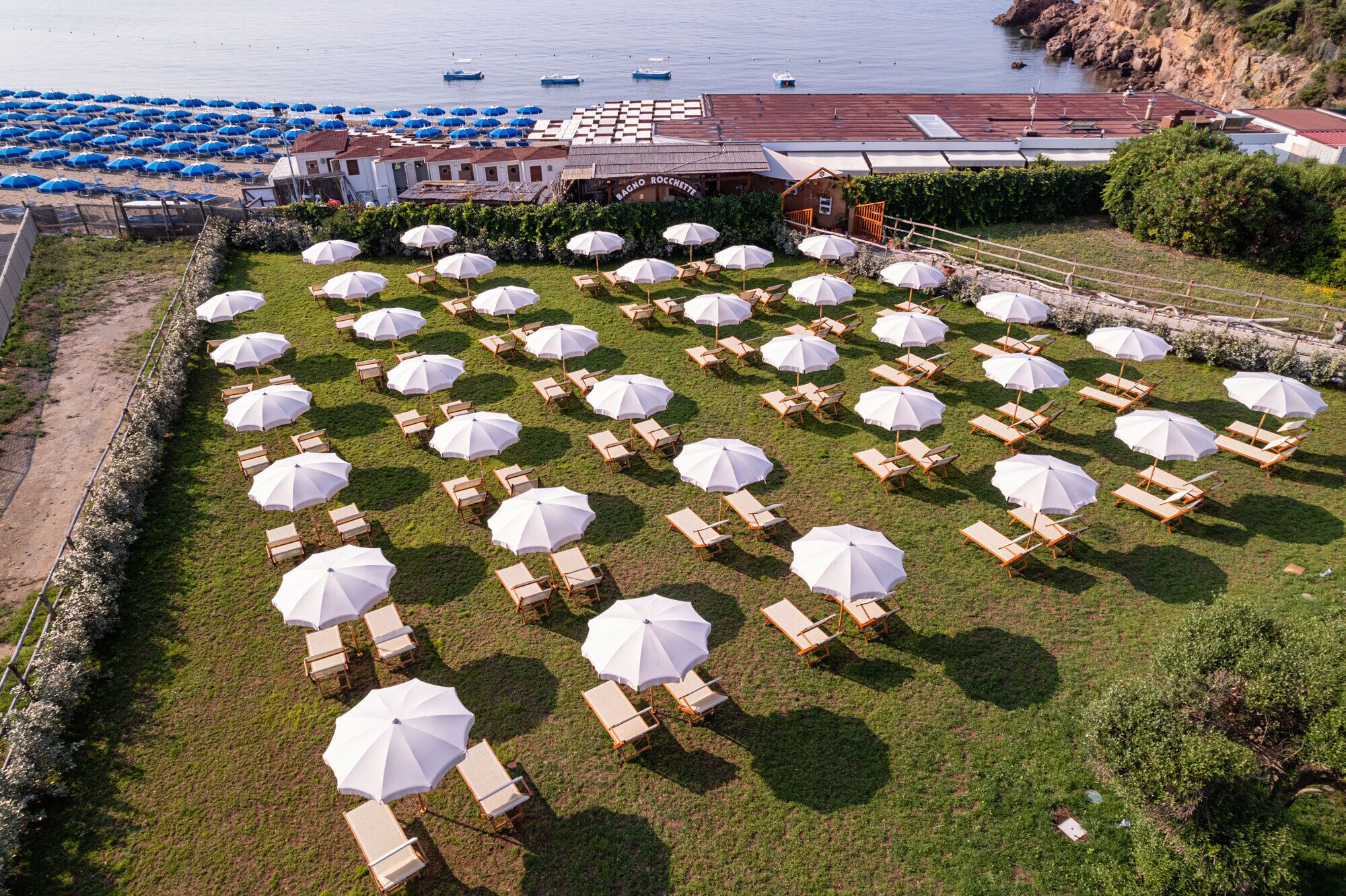 An outdoor seating area with white umbrellas and wooden chairs arranged in rows.