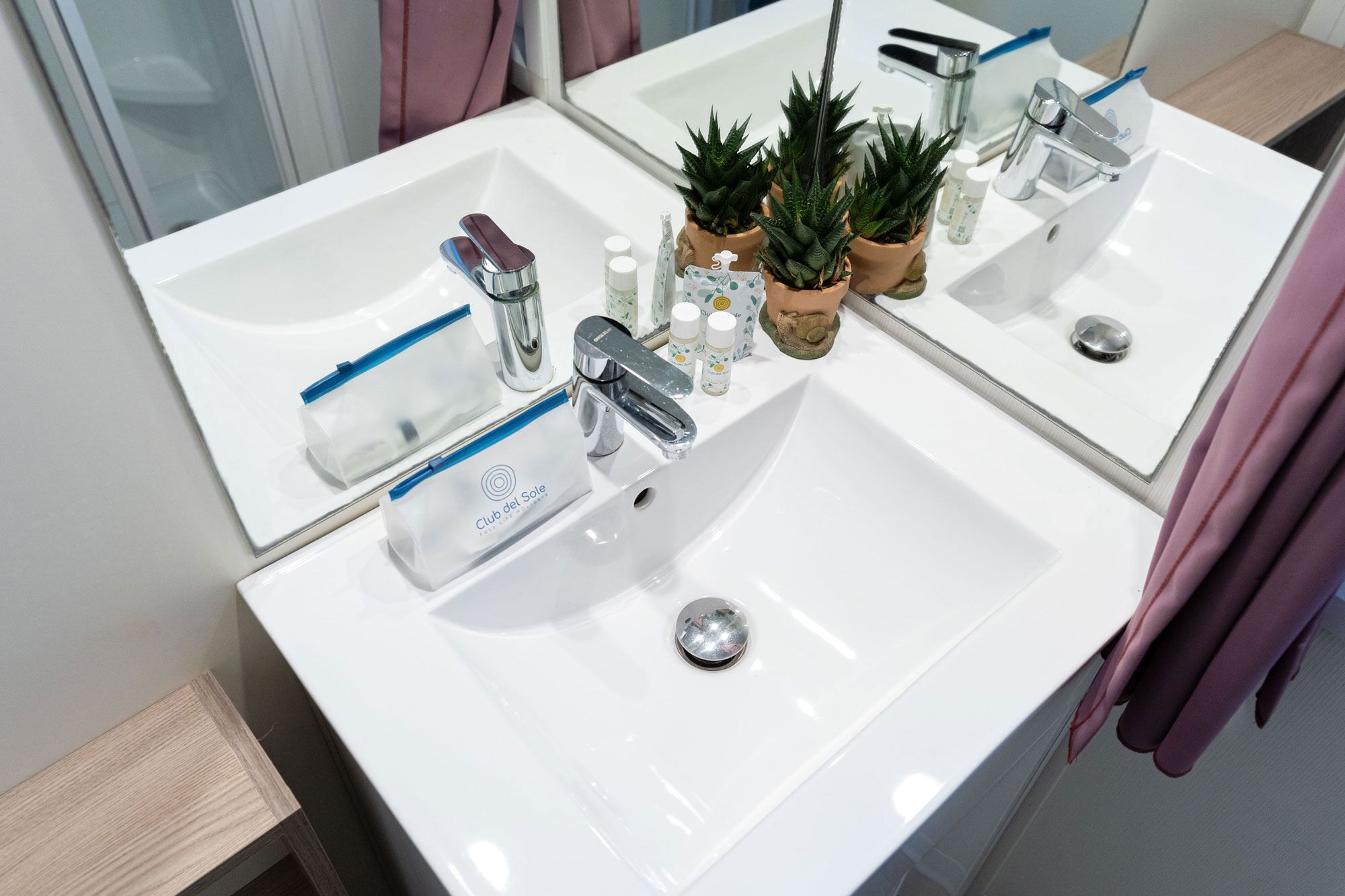 A bathroom with two sinks, a mirror, and various toiletries.