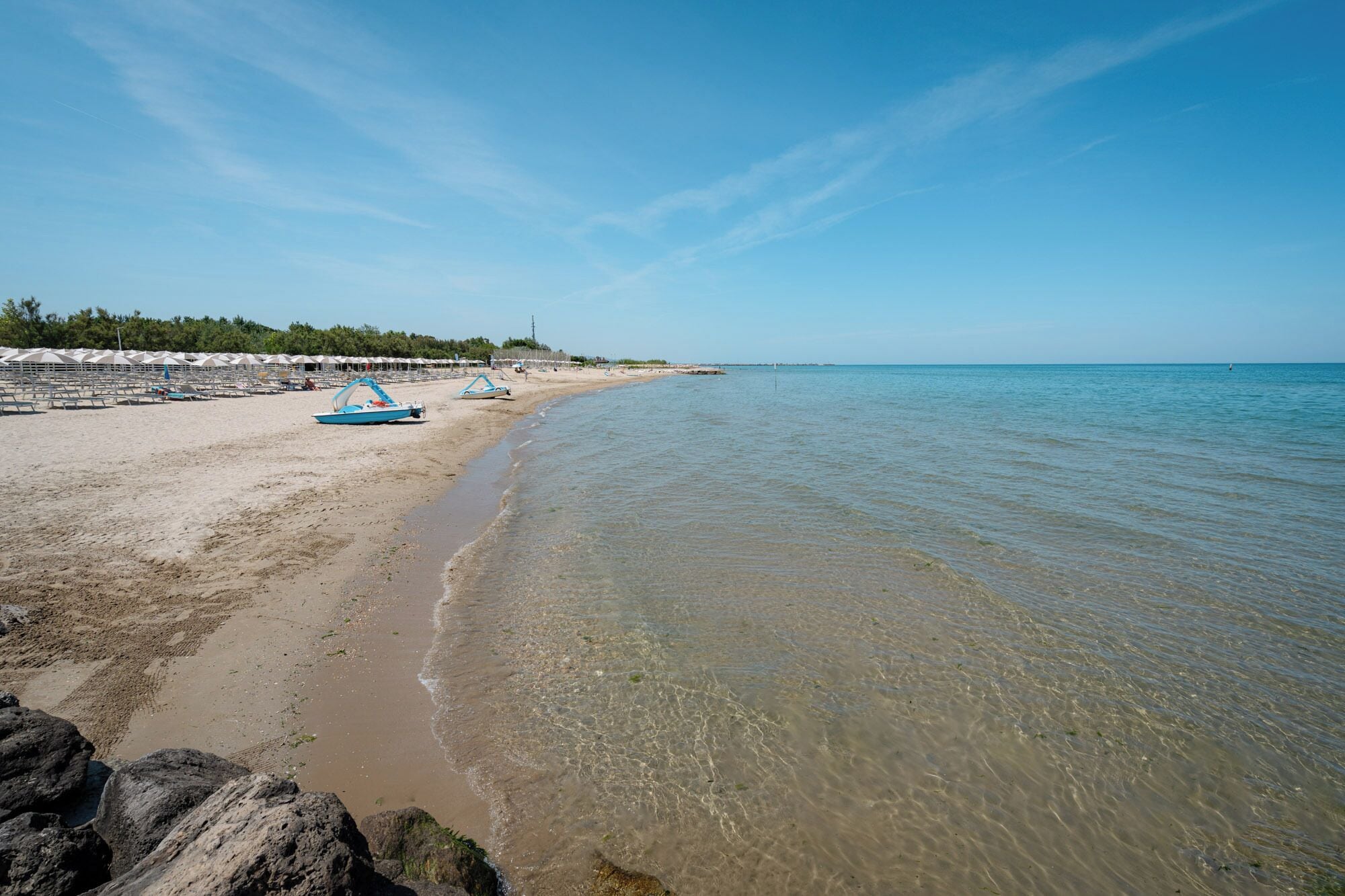 Privat strand, solstolar, parasoller och volleyboll