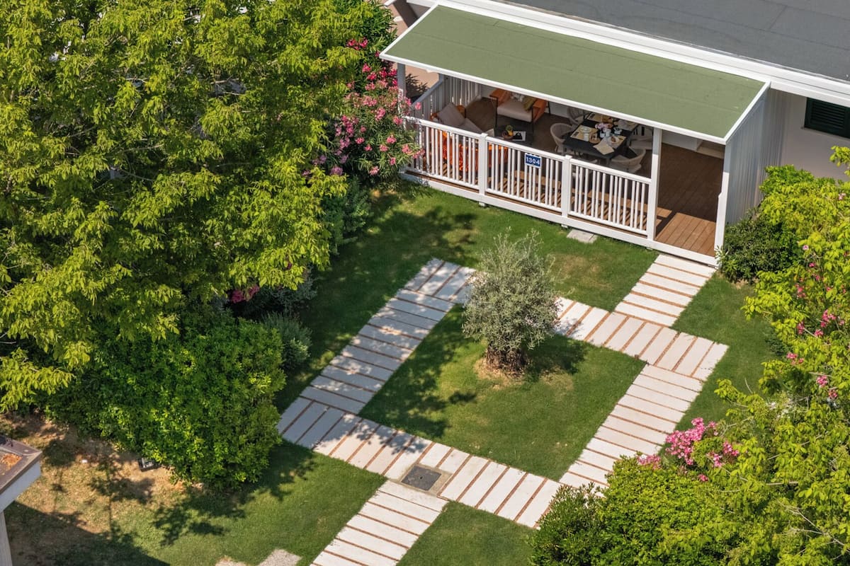 Un immobile residenziale con patio recintato, prato e vialetto.