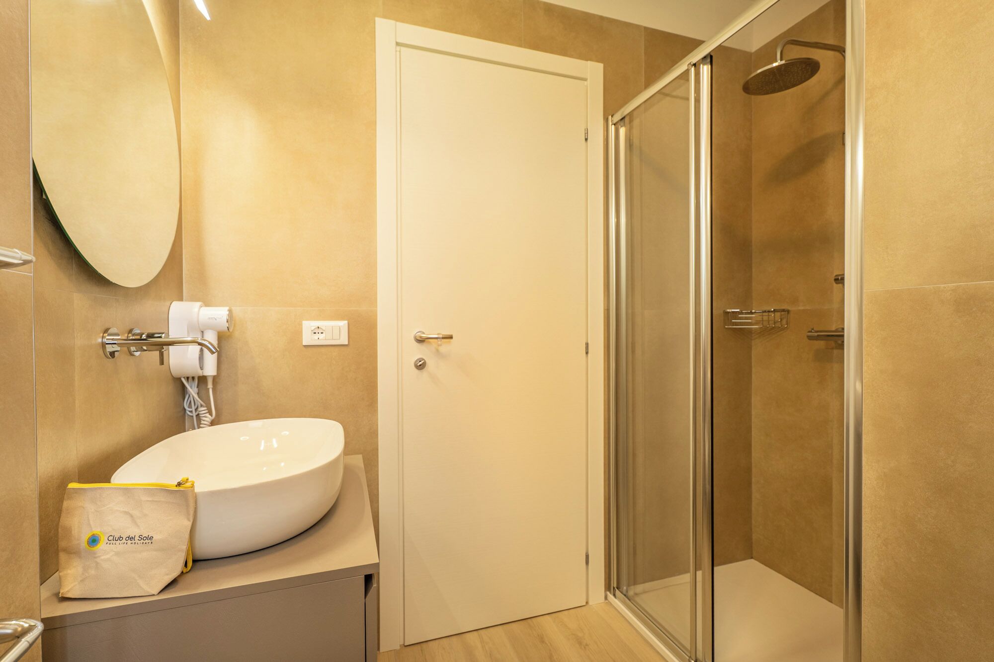 Ein Badezimmer mit weißem Waschbecken, einer Duschkabine aus Glas und einer Tür.