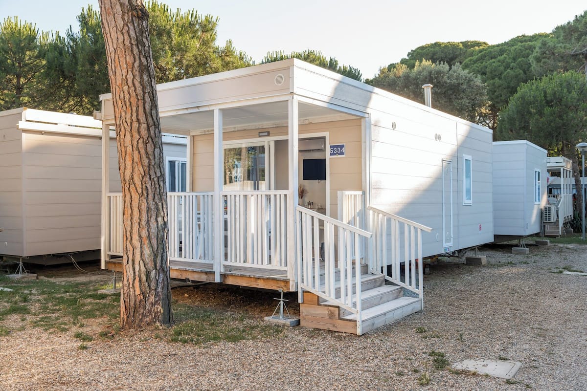 Una casa mobile con veranda e una piccola terrazza, circondata da altre abitazioni simili.