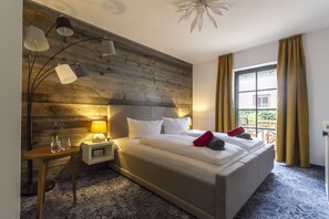 A modern hotel room with a large bed, wooden headboard, and a view of the outdoors.