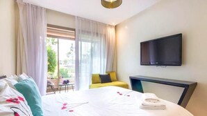Ein Hotelzimmer mit einem großen Bett, einem flachbildfernseher an der Wand und Blick ins Freie durch das Fenster.