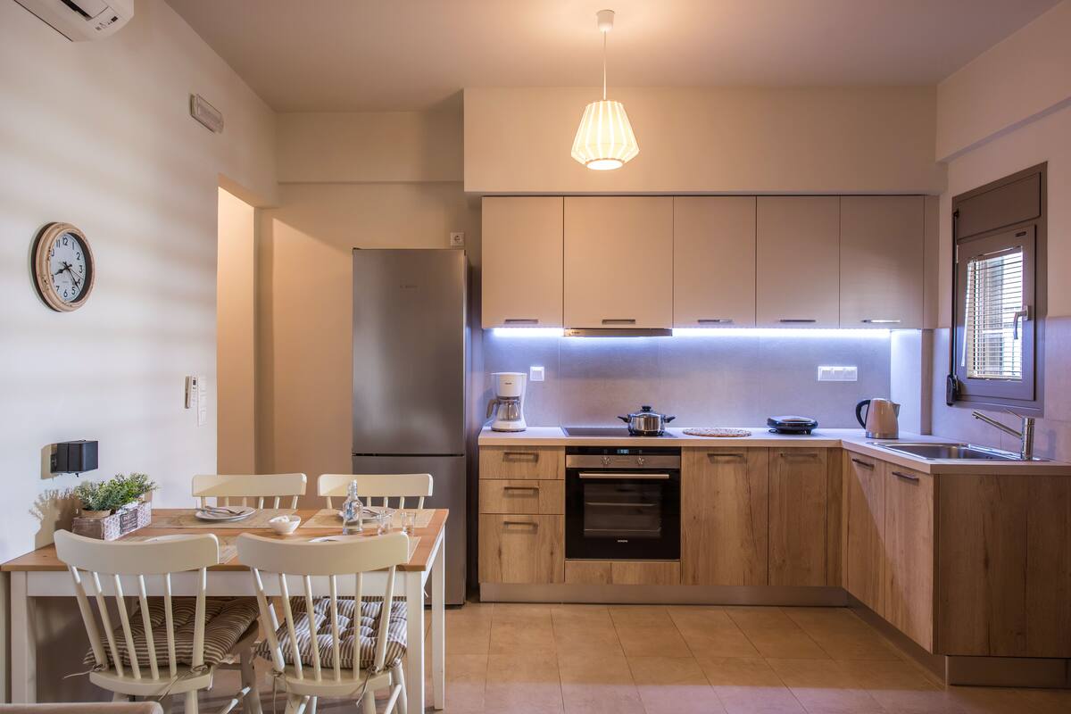 Eine moderne Küche mit Holzausstattung, einem eingebauten Backofen und einem Essbereich mit Tisch und Stühlen.