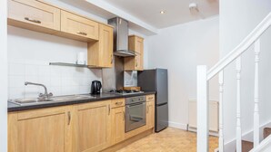 Una cocina moderna con armarios de madera, electrodomésticos de acero inoxidable y suelo de baldosas.