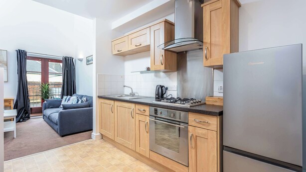 Una cocina moderna con armarios de madera, un refrigerador de acero inoxidable y un horno empotrado.