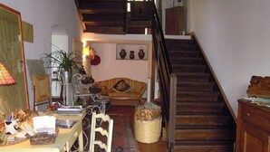 Uma sala de estar aconchegante com uma escada de madeira, uma mesa de jantar com cadeiras e um sofá.