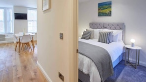Un dormitorio con cama, mesita de noche y un cuadro en la pared.
