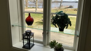 Una ventana con vista a un lago, un banco y un sendero.