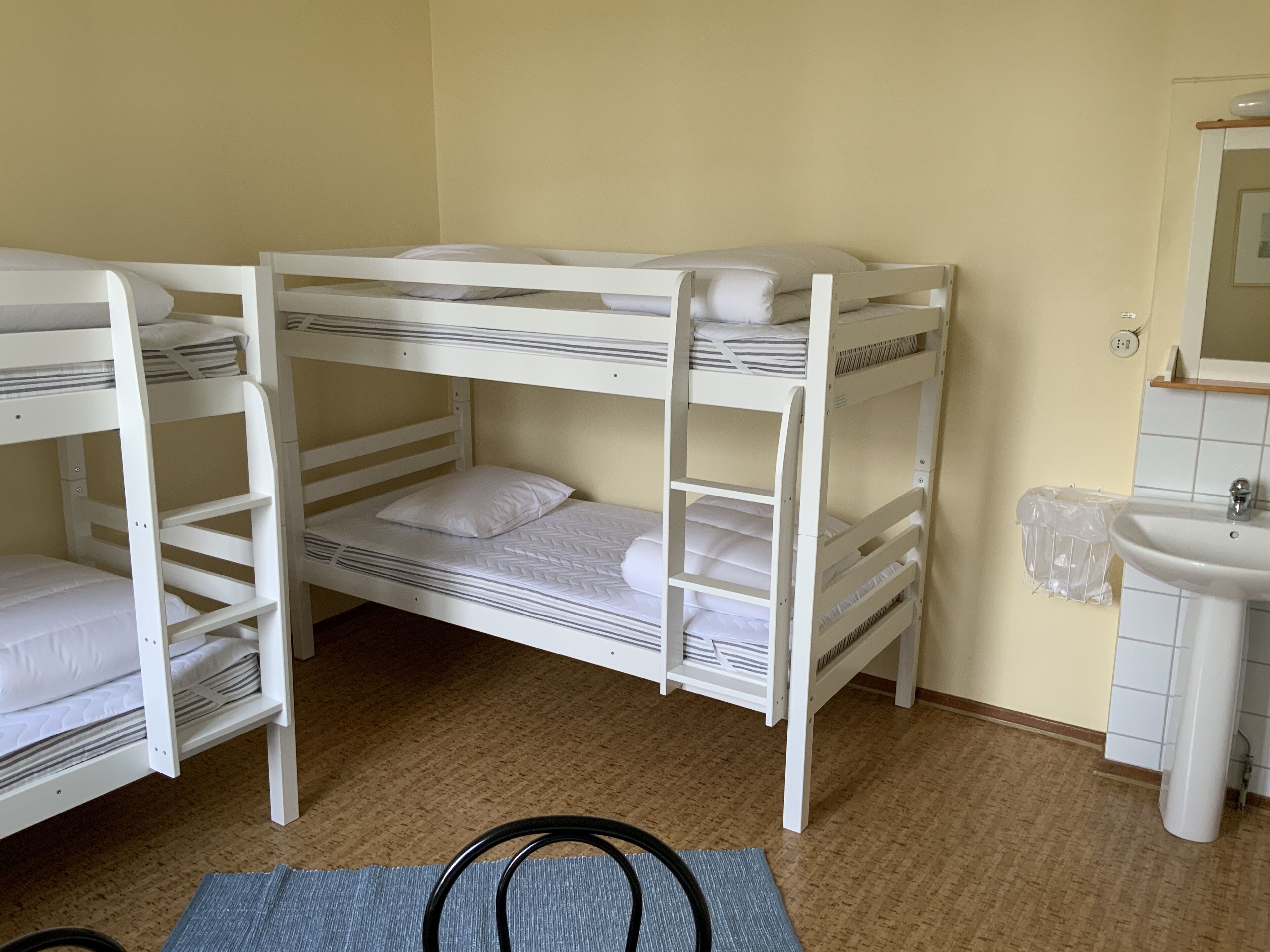 Una camera con letto a castello, lavandino e specchio.