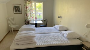 Un dormitorio con cama, una silla, una mesa y una ventana con cortinas.