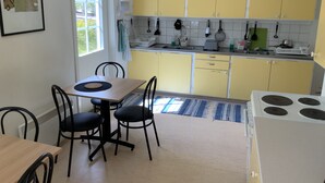 Una cocina con gabinetes amarillos, una estufa blanca y una zona de comedor con mesa y sillas.
