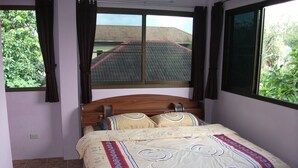 Ein Schlafzimmer mit Bett, Fenster und Blick auf ein Hausdach.
