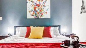 Une chambre d’hôtel équipée d’un lit, d’une table de chevet, d’une lampe, d’une machine à café et d’un plateau avec des tasses.