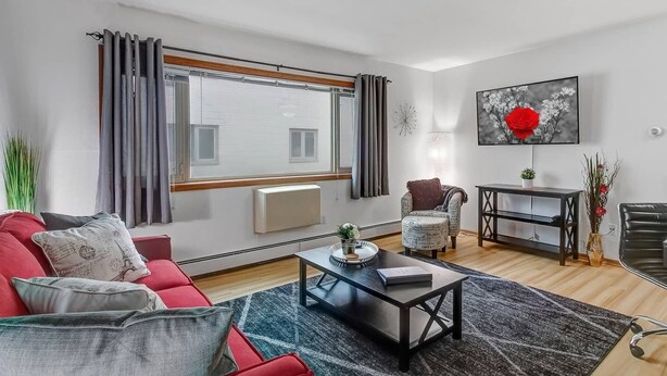 Un salon moderne avec un canapé rouge, un fauteuil à motifs, une table basse et un meuble TV noir.