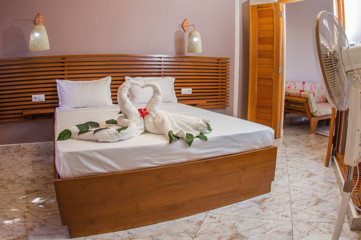 A neatly made bed with a wooden headboard, a bedside table, and a wall-mounted lamp.