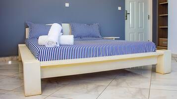 Una cama con ropa de cama a rayas, una mesita de noche y un armario de madera en una habitación con suelo de baldosas.