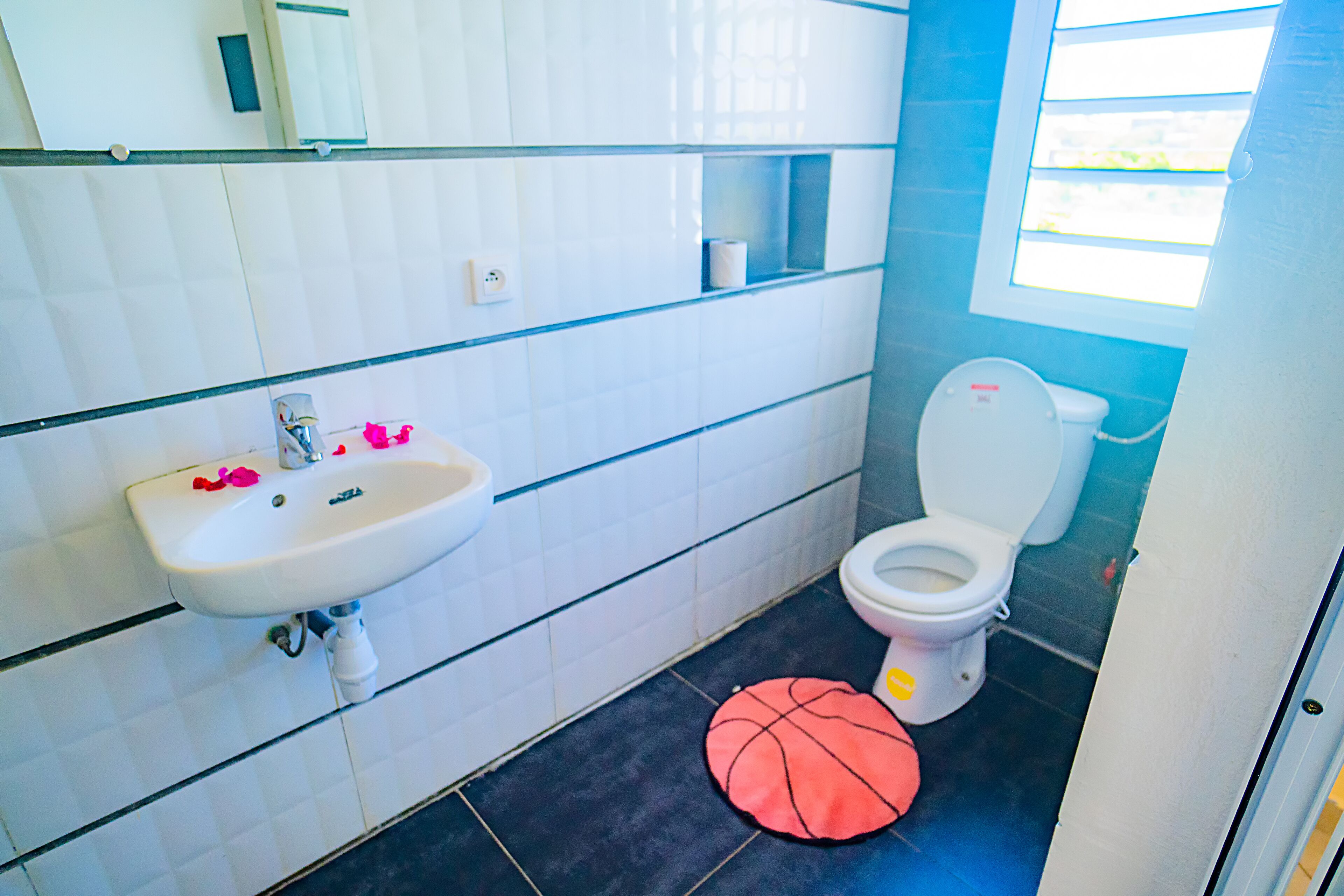 Un baño con lavamanos blanco, inodoro y ventana.