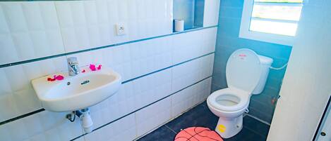 Un baño con lavamanos blanco, inodoro y ventana.