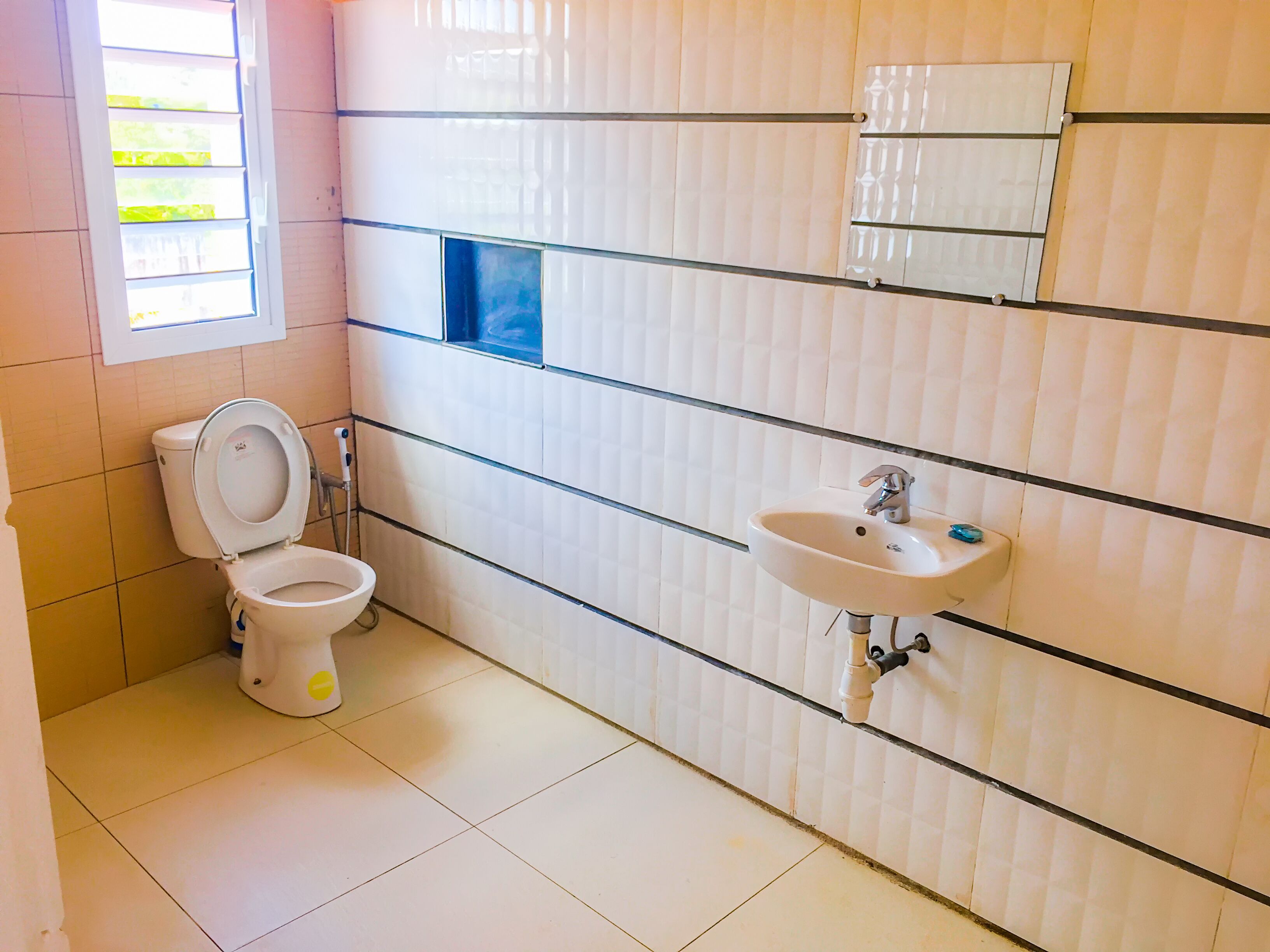 Une salle de bain avec des toilettes, un lavabo et une fenêtre.