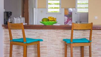 A kitchen with two wooden chairs, a green fruit bowl, and a coffee maker.