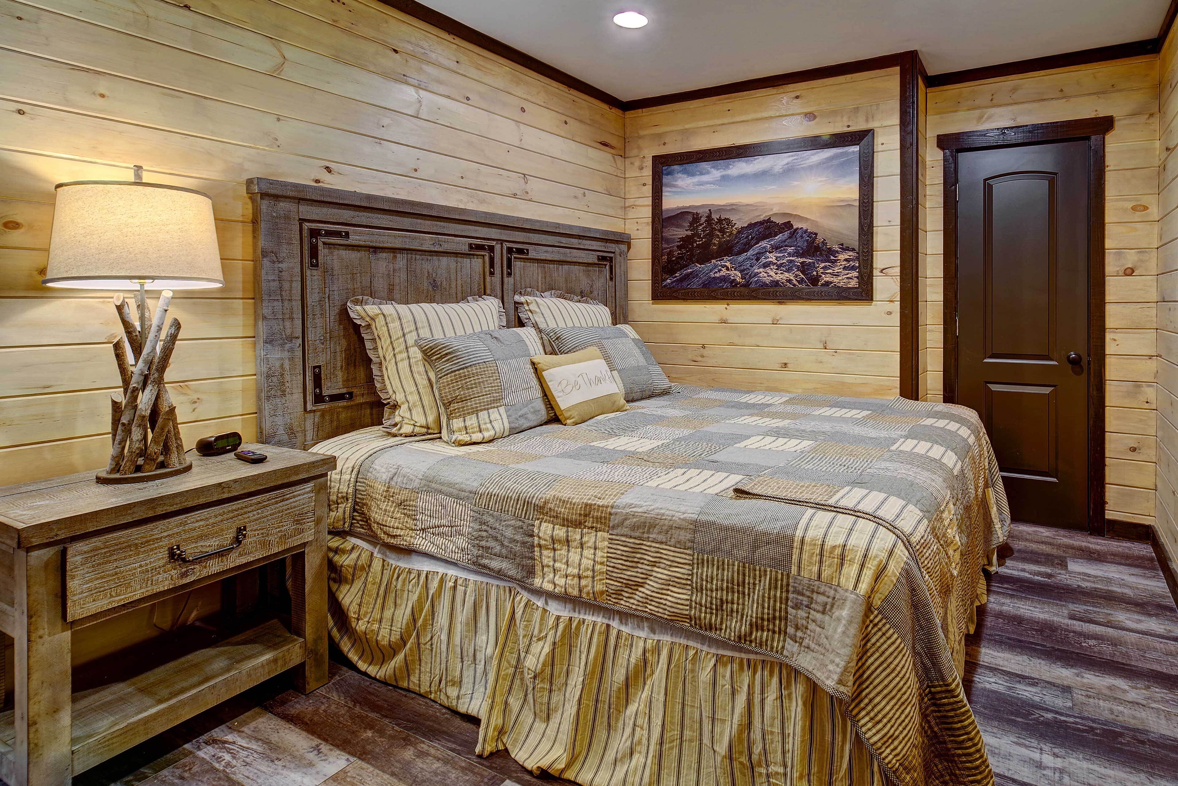 A wooden-paneled bedroom with a bed, nightstand, lamp, and a painting on the wall.