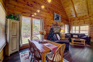 L’intérieur d’un chalet chaleureux, avec une table à manger en bois, des chaises, un sapin de Noël et un canapé en cuir.