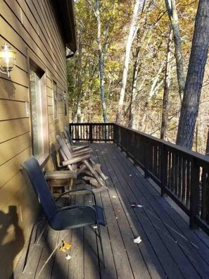 Eine Holzterrasse mit Geländer, einer Bank und einem Stuhl.