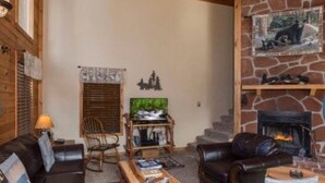 A cozy living room with a fireplace, leather sofas, a wooden coffee table, and a bookshelf. - The Heart of Tennessee (Sevierville)