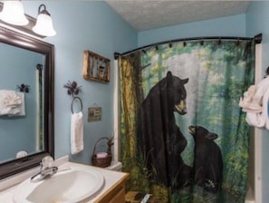 Ein Badezimmer mit Waschbecken, Spiegel und einer Duschvorhang mit Bärenmotiven.