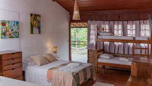 Un dormitorio con una cama litera, una cama individual, muebles de madera y obras de arte en las paredes.