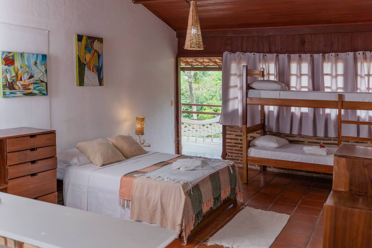 Um quarto com uma cama beliche, uma cama de solteiro, móveis de madeira e obras de arte nas paredes.