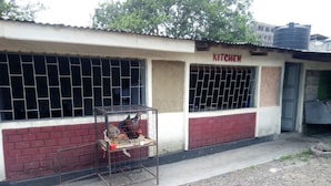 A building with a sign that reads "KITCHEN" above a window with metal bars. - Queens Village Hotel (Nakuru)