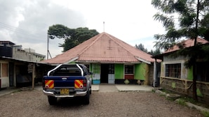 A building with a red-tiled roof and a sign that reads "Queens Village". - Queens Village Hotel (Nakuru)