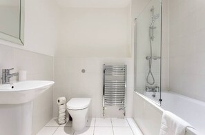 A modern bathroom with a white sink, toilet, and shower area.