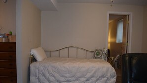 Un dormitorio con una cama, un aparador y una silla.