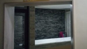 A reception area with a sign labeled "RECEPTION" above a counter with a stone-textured wall behind it. - Skyline Hotel & Suites (Nakuru)