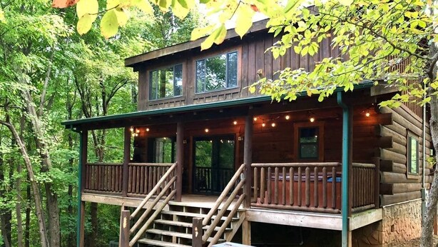 Eine Hütte mit Veranda, Grill und einer Treppe zum Eingang.
